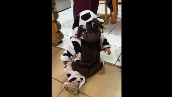Little girl in cow costume bumps into chair in playful moment in Santiago, Chile
