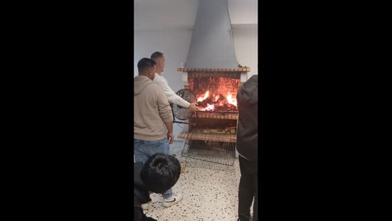 Man holds fan to intensify flames to the fireplace in Barcelona, Spain