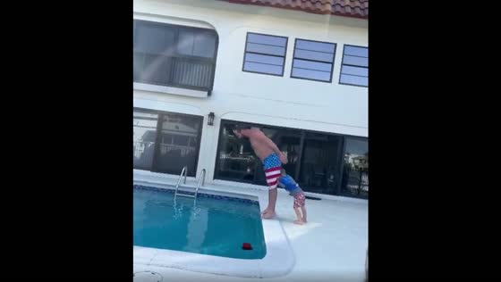 The child attempts to push his father into the pool, and he ends up falling in too