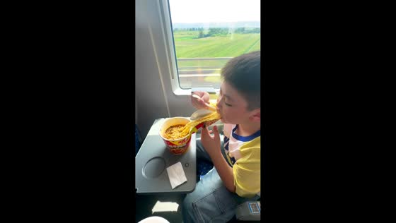 Boy uses instant noodle lid as a makeshift filter while eating on train in Shaanxi, China