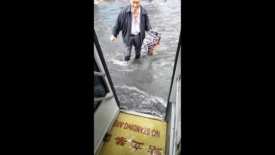 Man walks through a flooded road to board a bus in Fuyang, Anhui, China