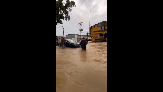 Man carries woman through flooded street in Recife, Brazil
