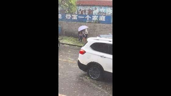 Man shields child from hailstorm under umbrella in Guizhou, China