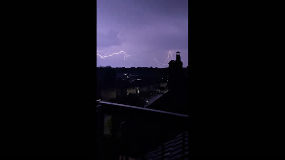 Father films son on balcony with lightning strikes in background in London, United Kingdom