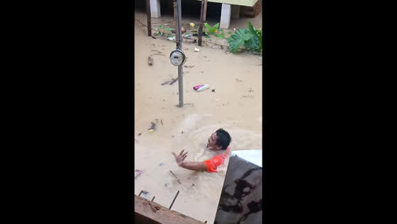 Man swims in neck-deep flood during heavy rain in Zamboanga City, Philippines
