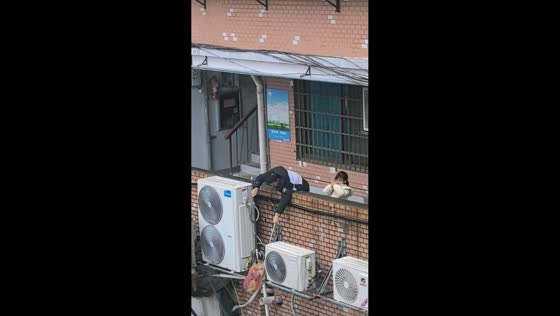 Father and daughter rescue stranded kitten from air conditioner unit in Jiangxi, China