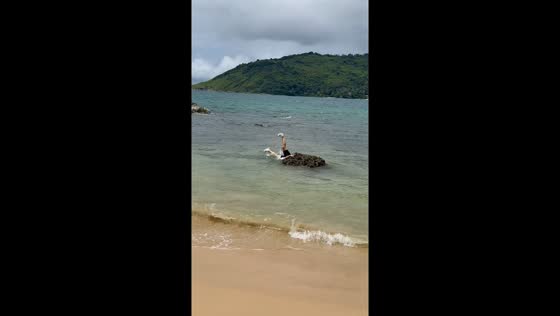 Friend slips into water while posing on rocks in Phuket, Thailand