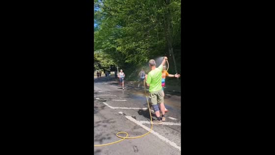 Man cools down Leeds Marathon runners with hose shower in West Yorkshire, England