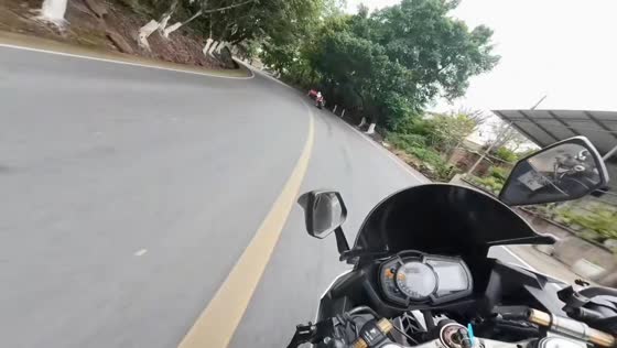 Two motorcycle riders crash beside a canal while taking a sharp turn in Guizhou, China