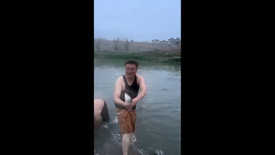 Man catches fish with bare hands in river in Henan, China