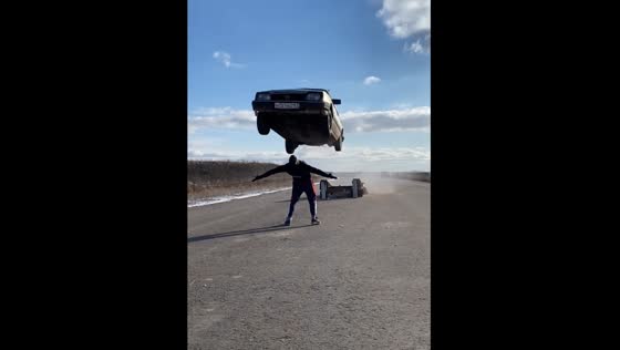 A car performs a long jump, and a guy is under it