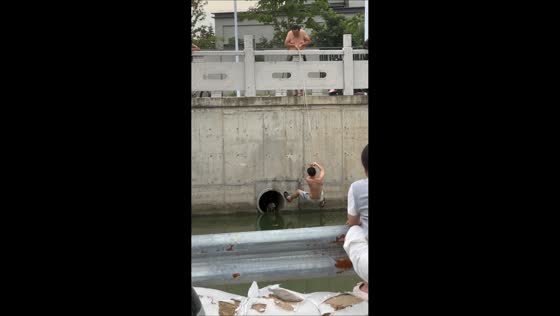 People rescue dog trapped in drainage pipe by river in Jiangsu, China