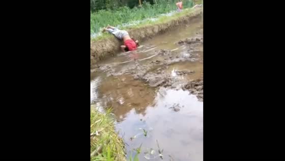 Young boy takes a spill into rice field stream while washing hands in West Sumatra