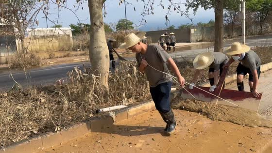 Three men work together to remove mud from a road in Guangxi, China