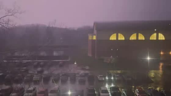 Lightning briefly illuminates parked cars outside building in Athens, Ohio, USA
