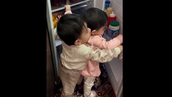 Twins play with open fridge in Jolfa, Iran
