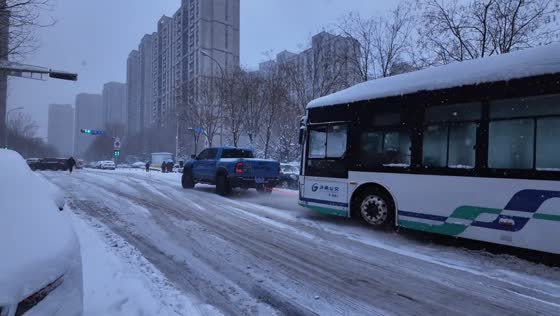 Pickup truck pulls a stuck bus on a slippery road in Shandong, China