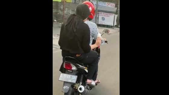 Man spots woman carrying ice cream while riding motorbike in Bandung, Indonesia