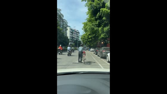Driver patiently waits as elderly cyclist struggles to start riding in Guangdong, China