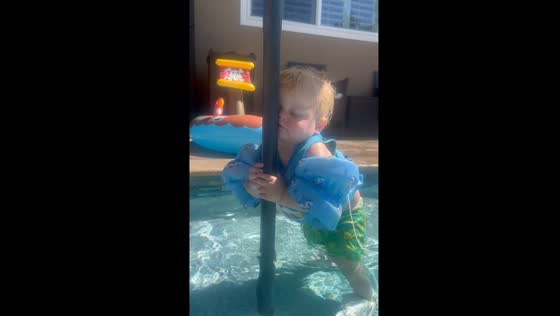 Boy falls asleep in pool while holding umbrella