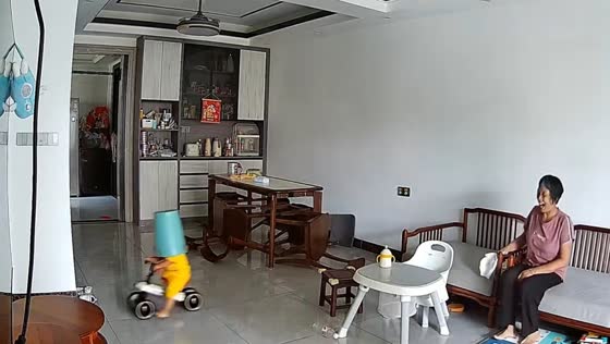 Toddler rides toy tricycle with trash can on head in Guangdong, China