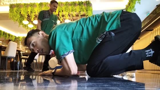 Man slips while employees clean floor in Yogyakarta, Indonesia