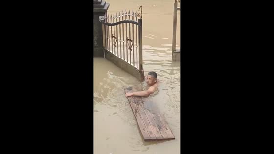Man swims through flooded yard to open gate in Fujian, China