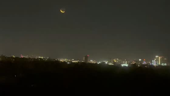 Crescent moon glows above Cambridge skyline at night in Massachusetts, USA