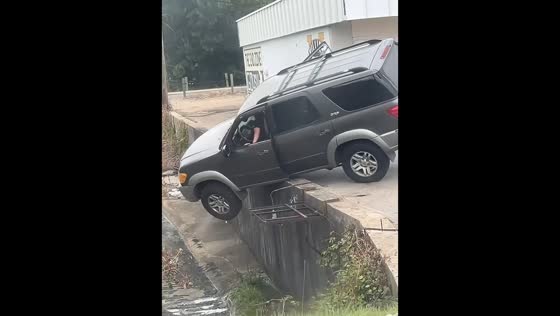 SUV flips into drainage ditch after teetering over parking lot ledge in Hattiesburg, USA