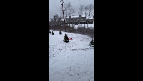 Daughter enjoys snow sliding fun in the backyard in Florence, Kentucky, USA