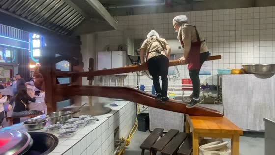 Two women ride noodle sheeting machine to cook large dough in Shanxi, China
