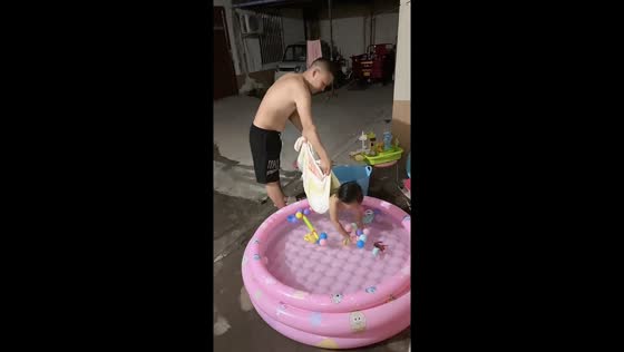 Father gently swings child toward kiddie pool to pick up toys in Henan, China