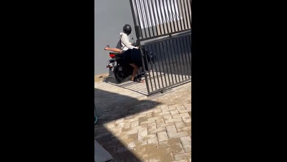 Motorcycle passenger falls off after bag gets caught on gate in Malang