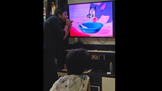 Man entertains child by syncing actions with Tom and Jerry on TV