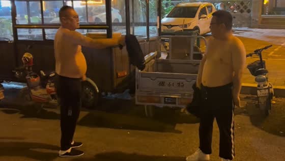 Men fight playfully with shirts on roadside in Hebei Province