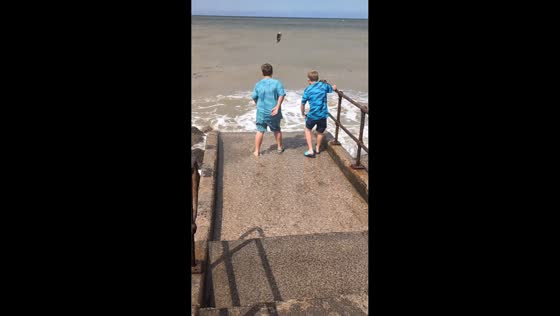 Boy loses Croc in water while playing at beach slipway in Towyn, Wales, UK,