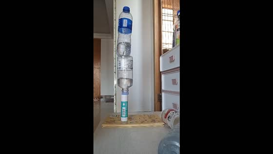 Two water bottles land upright on a glue stick in a bottle-flipping challenge in Guangdong, China