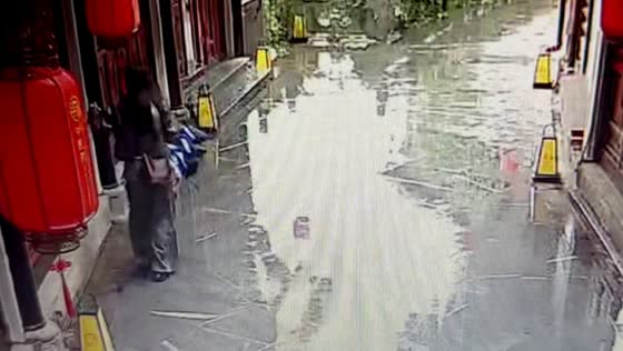 Woman slips and falls while walking in rain in Chongqing, China
