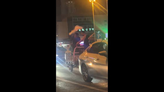 Three men joyfully dance on a moving tricycle in Hebei, China