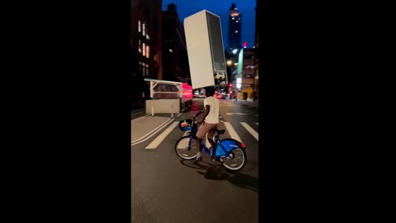 Man balances refrigerator on head while riding bicycle in Chicago