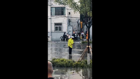 Police officer clears clogged drainage to reduce flooding on road in Shanxi, China