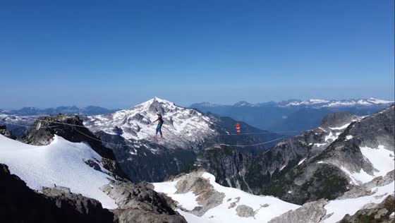 Slackliner enjoys summer highlining between mountain peaks in Whistler, Canada