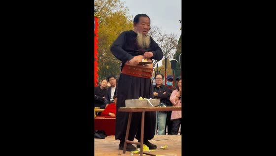 Street performer chops vegetables with a knife on his stomach in Hebei, China