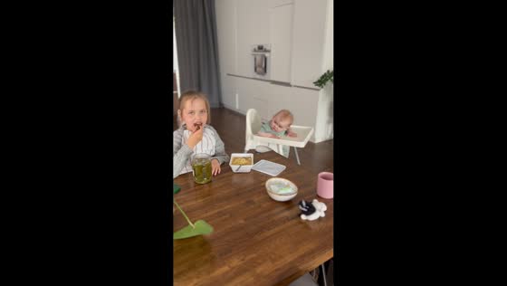Baby can't take eyes off her sister eating lunch in Chelyabinsk, Russia