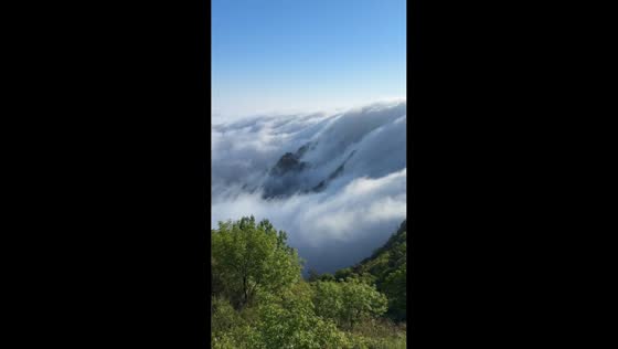 Cloud waterfall flows over mountain ridge at Daheishan scenic area in Dalian, China