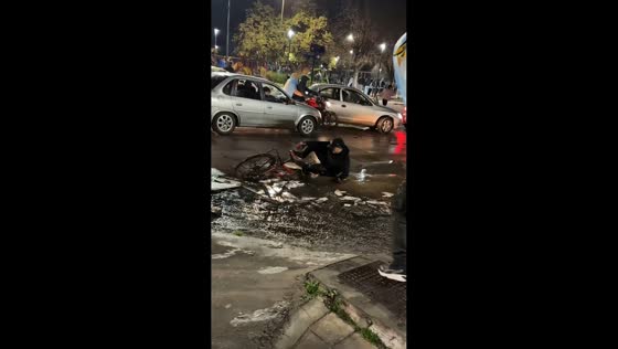 Cyclist slips in muddy puddle while crossing busy street in González Catán, Argentina