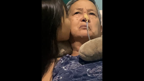 Elderly woman with nasogastric tube shares emotional moment with granddaughter