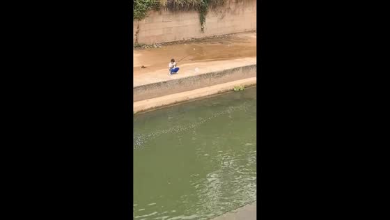Boy reels in large fish from riverside in Guangdong, China
