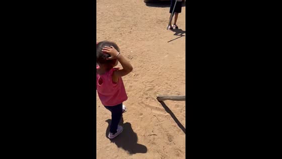 Girl walks while holding a mouse by its tail in San Quintin, Mexico