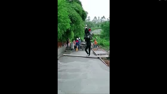 Ingenuity in action: friend carries motorbike across wooden plank amid road repair obstacle